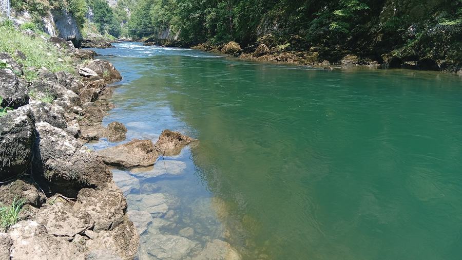 Quiet emerald pool on the Vrbas river with rocky bank and canyon walls, near Banja Luka
